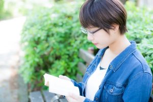 公園のベンチで読書をする文学少女