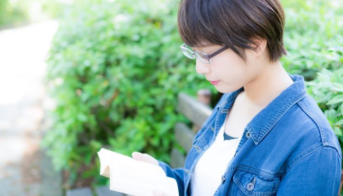 公園のベンチで読書をする文学少女